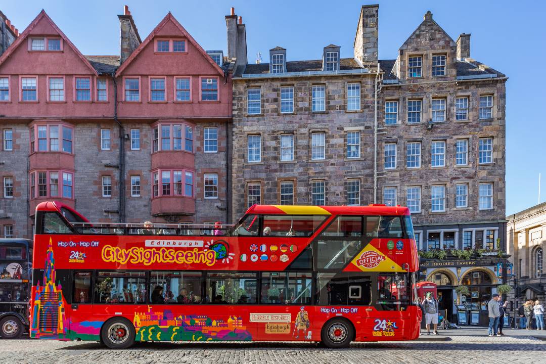 A photo of a Edinburgh hop-on hop-off tour bus driving through the streets.