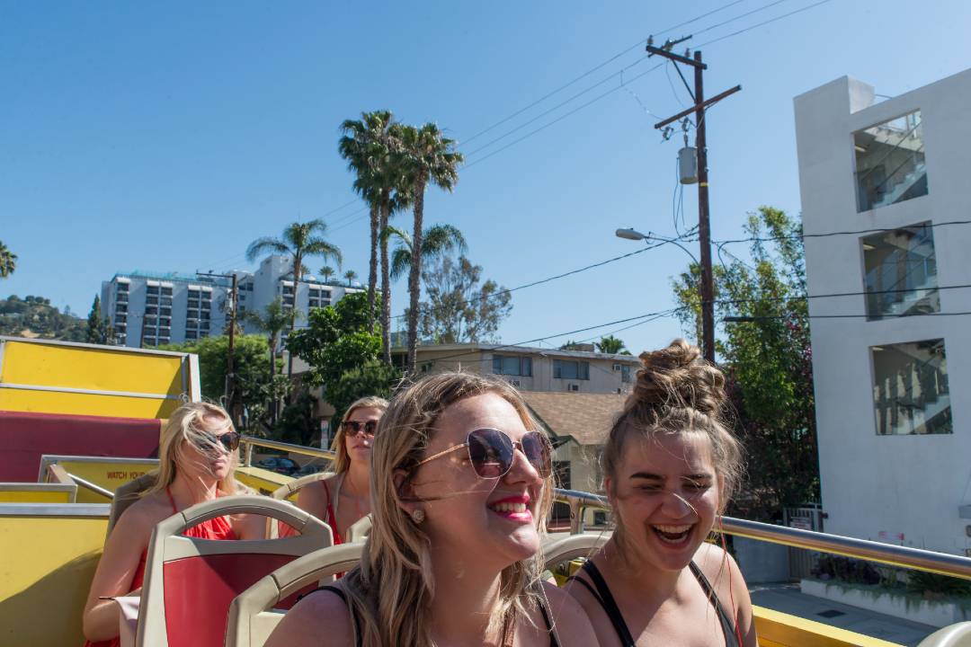An open-top bus tour driving through Los Angeles.