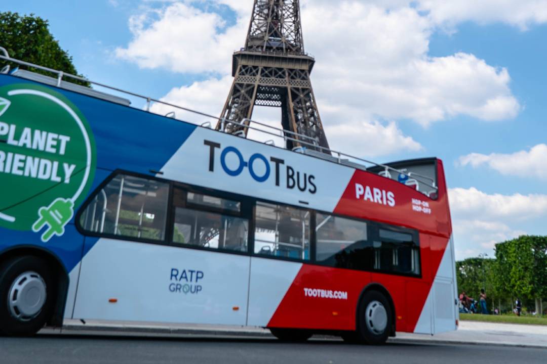A Paris bus tour passing by the Eiffel Tower.