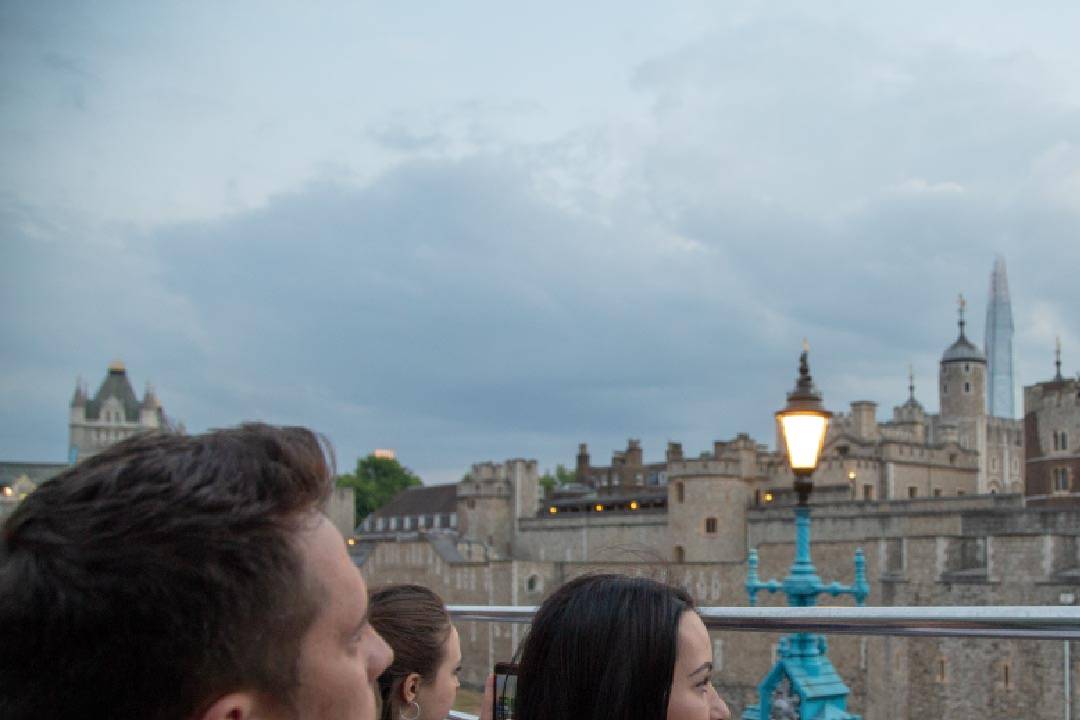 A group of people looking at the Tower of London in the evening.