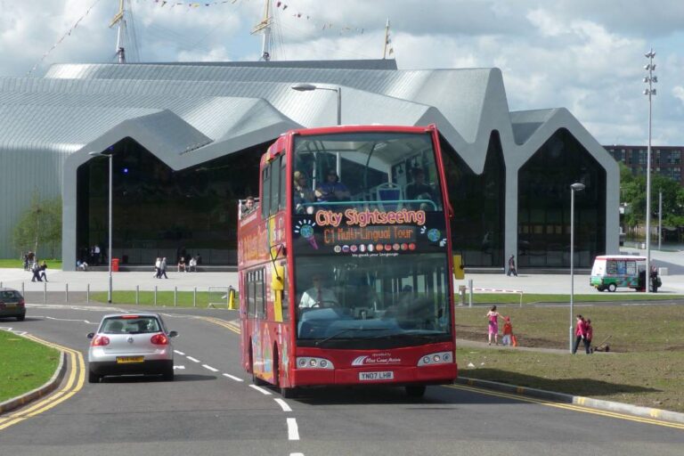 A Glasgow hop-on hop-off tour bus driving away from the Riverside Museum.