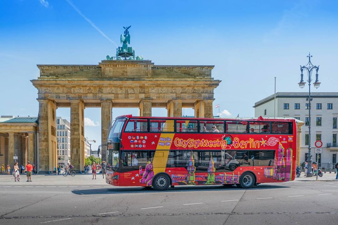 A photo showing a hop-on hop-off Berlin tour driving past the Brandenburg Gate.