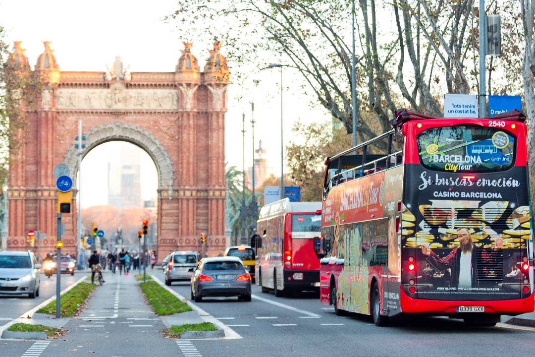 A bus tour driving towards the Arc de Triomf in Barcelona.