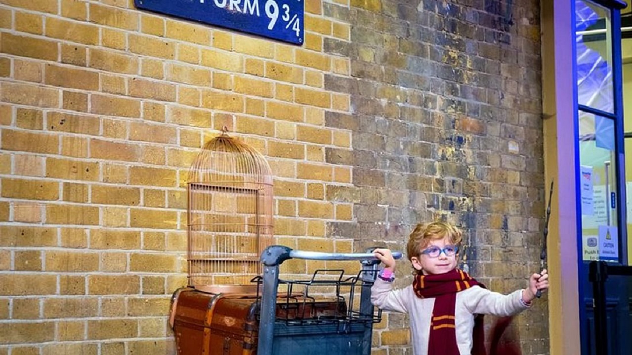 A child standing next to the Harry Potter trolley.
