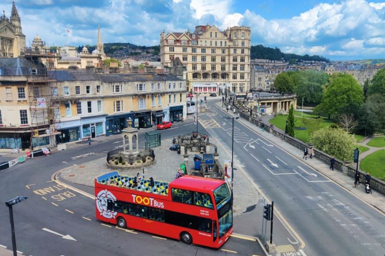 A photo of a bus tour driving in Bath.