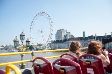 A photo from the top of an open-top hop-on hop-off tour bus showing the London Eye in the distance.