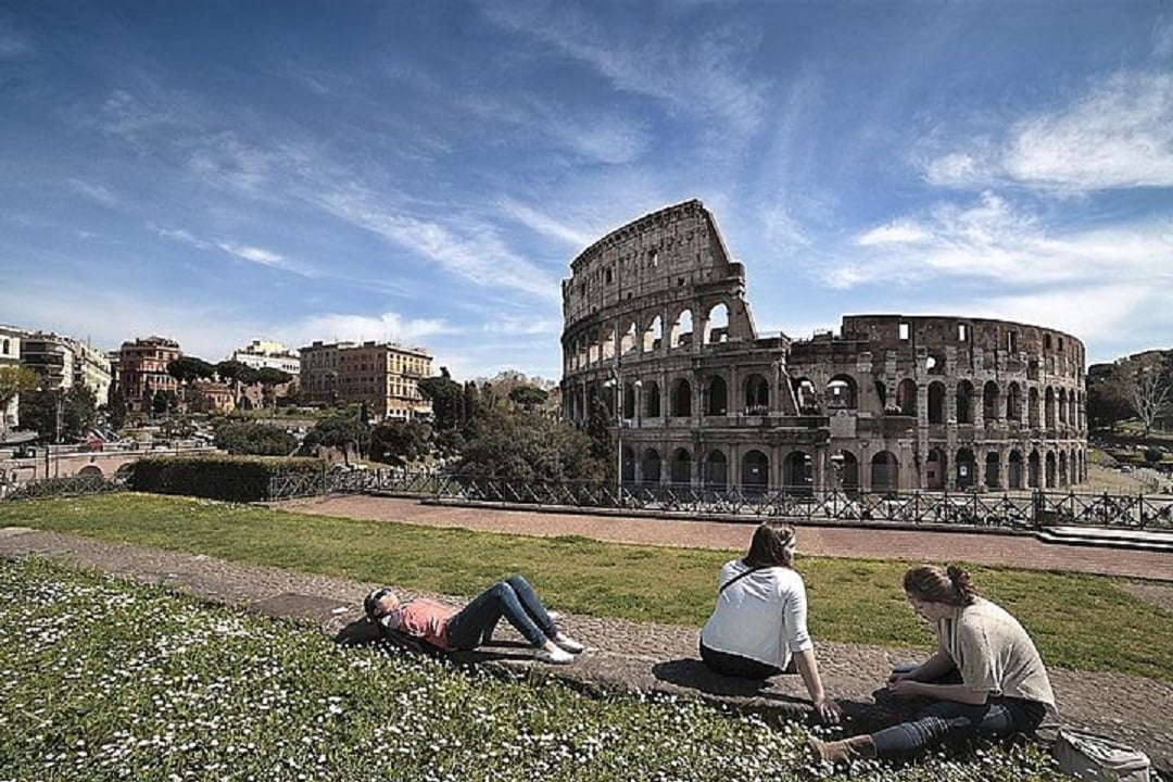 People sitting in front of Rome's Colosseum.