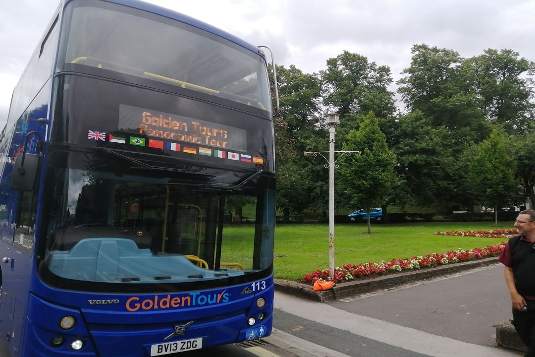 The front of a York Bus Tour driving past trees.
