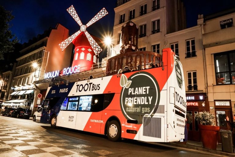 A Paris night tour driving down the street.