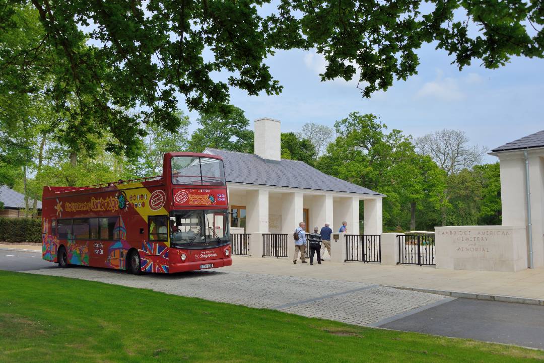 A photo of an open-top bus tour driving through Cambridge.