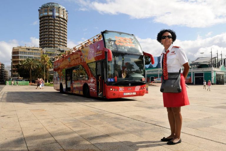 A woman standing in front of a Gran Canaria bus tour.