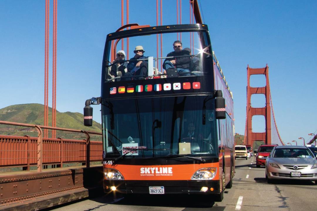 An open-top bus tour crossing a bridge in San Francisco.