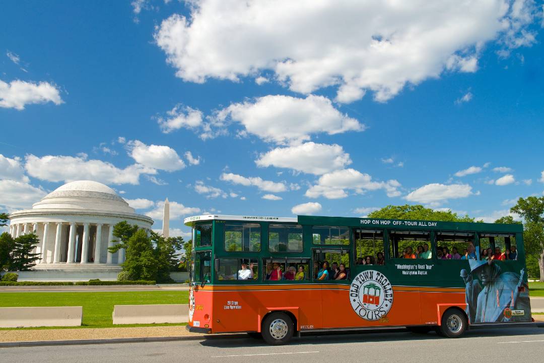 A Washington DC bus tour driving past the Thomas Jefferson memorial.
