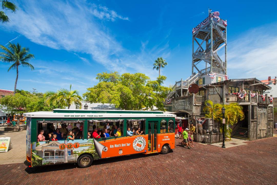 A photo showing a hop-on hop-off tour in Key West in front of a watchtower.