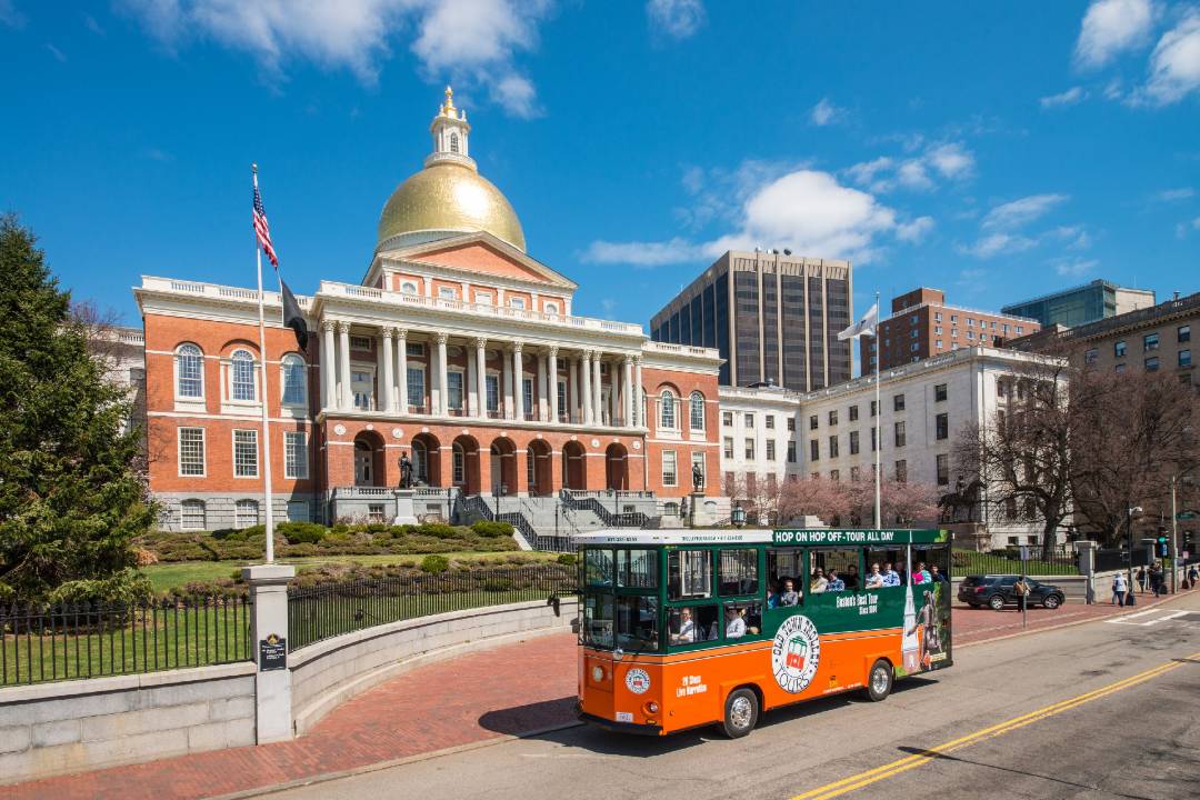 A Boston bus tour driving past the Massachusetts state house.