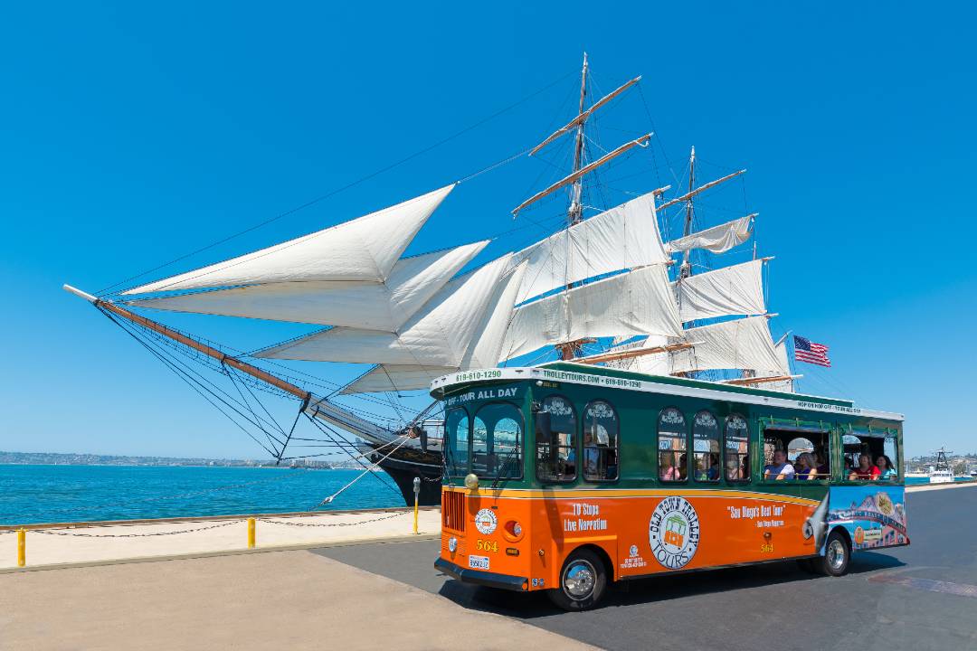 A photo of a San Diego hop-on hop-off tour in front of a large ship.