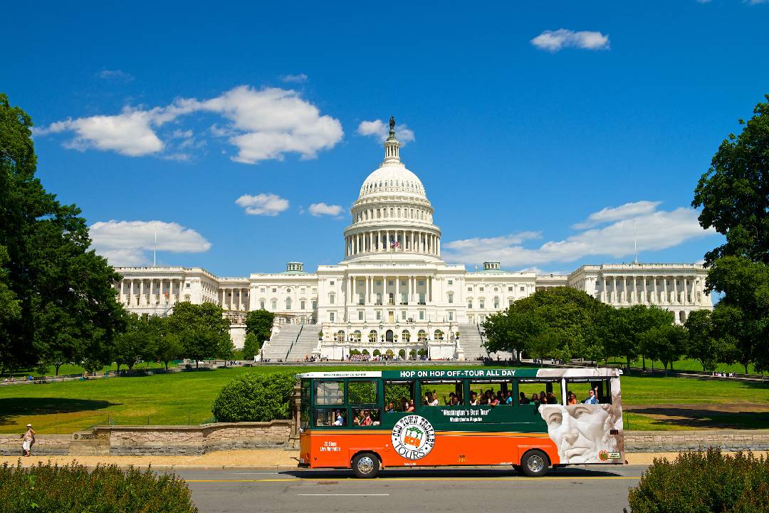 A bus tour driving past the US Capitol building.