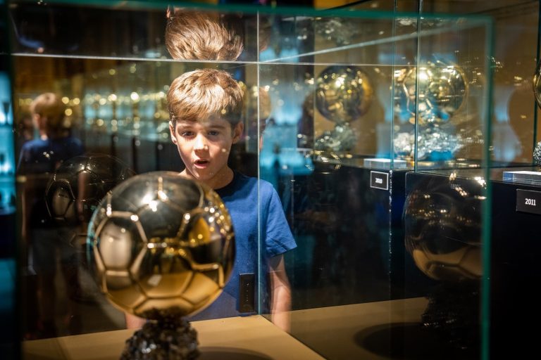 A photo of a young boy looking at a football trophy.