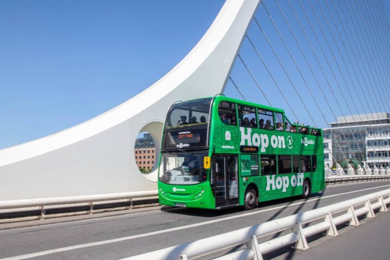 A hop-on hop-off Dublin sightseeing tour driving across a bridge.