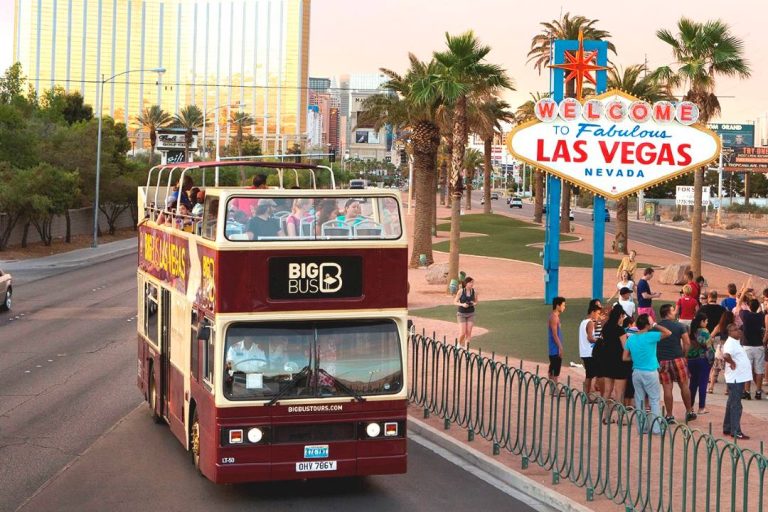 A photo of a Las Vegas bus tour passing by the Welcome to Las Vegas sign.