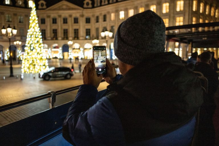 A photo of people taking photos of Christmas lights in Paris.