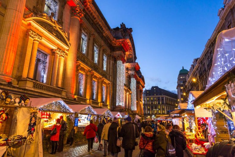 A photo of people walking through a street in Brussels filled with Christmas lights.
