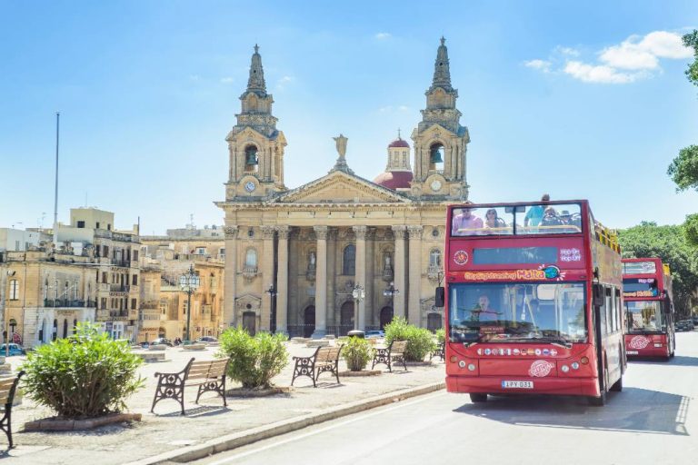 A Malta Bus tour passing The Saint Publius Parish Church.