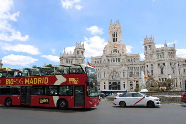 A photo showing an open-top bus tour driving past Cybele Palace.